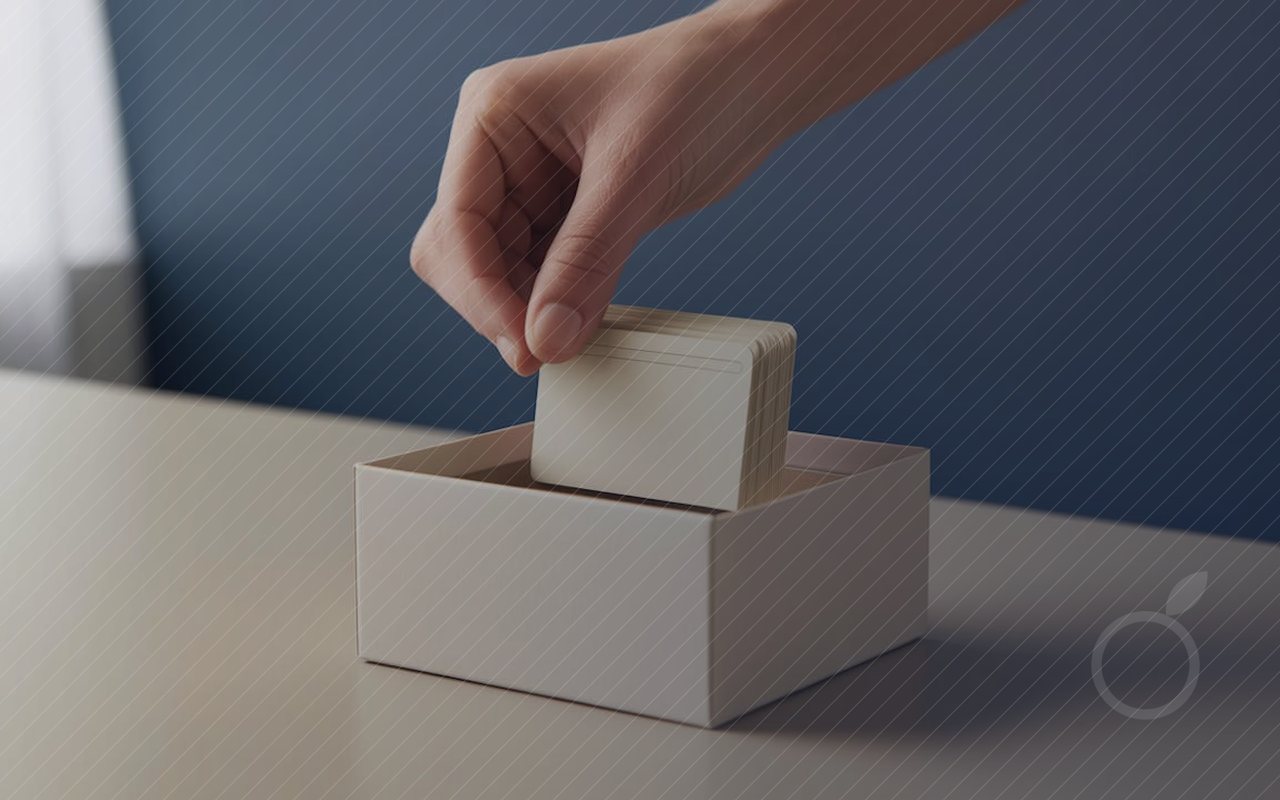 Une main glisse une fiche dans une boîte de rangement où les fiches sont déjà classées.