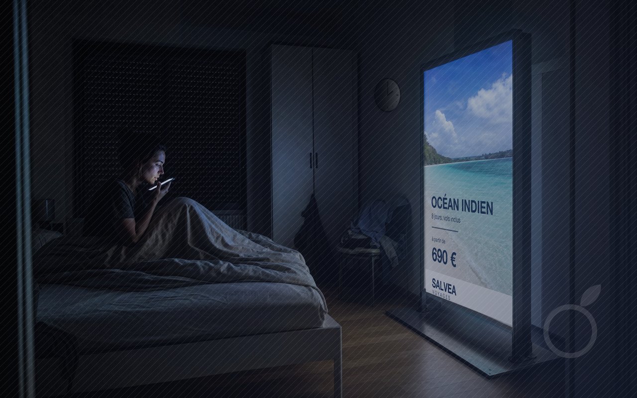 Panneau d'abribus rétroéclairé au pied d'un lit obscur, illustrant l'arrivée de ChatGPT Ads en France dans l'espace privé.